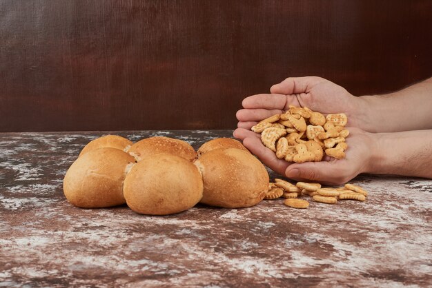 크래커와 함께 빵 굽는 사람의 손에 빵 롤빵.
