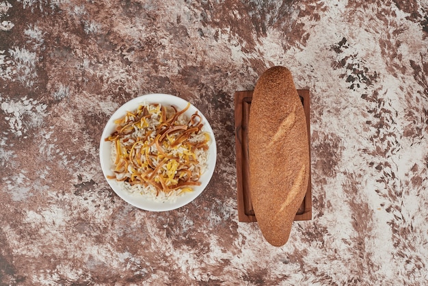 Bread bun on marble with rice garnish.