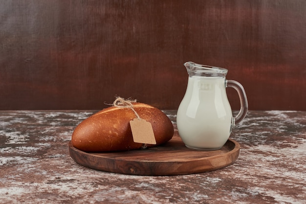 Bread bun on marble with tag and a jar of milk.