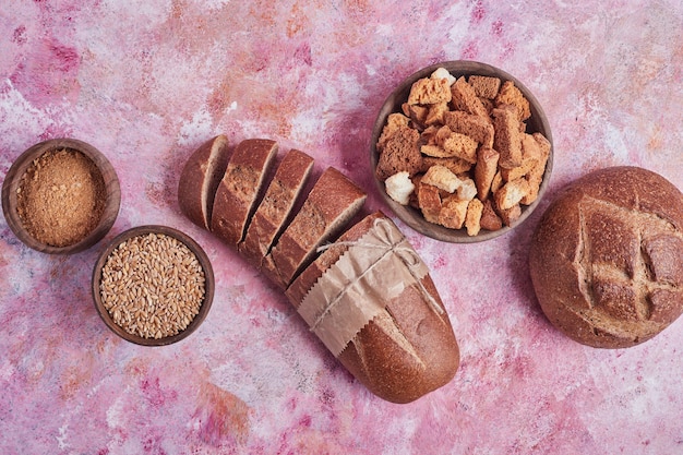 Bread buns and crackers on pink table.