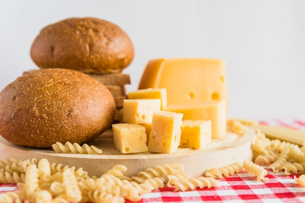 Bread and cheese on plate near scattered pasta