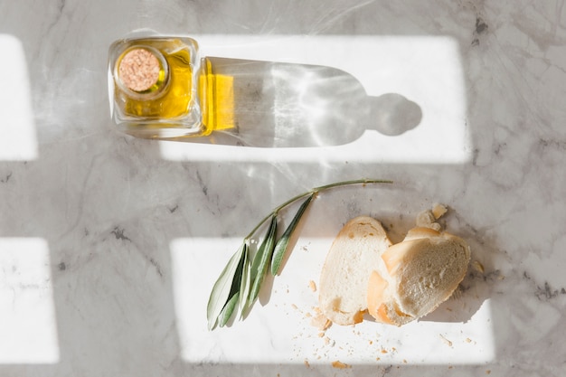 Free photo bread and closed oil bottle on white marble