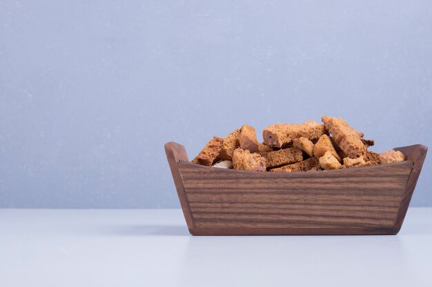 Bread crackers in a wooden tray on blue backdrop in the center