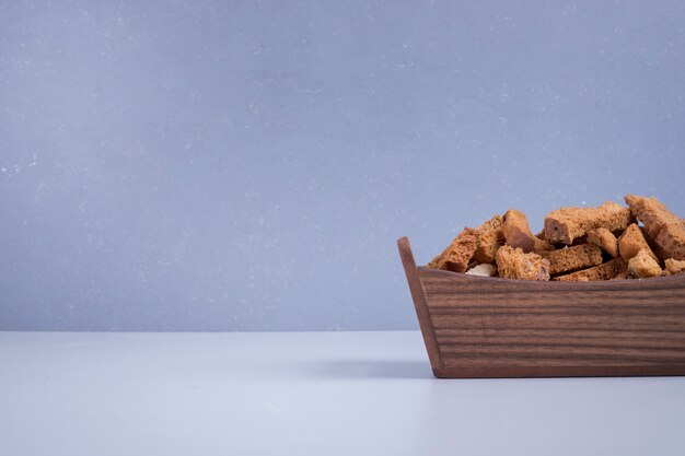 Bread crackers in a wooden tray on blue.