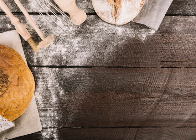 木製の厚板に小麦粉を散らしたパンと台所用具