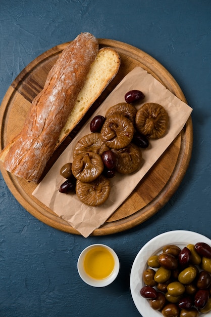 Bread long loaf, fig and dates on wooden board