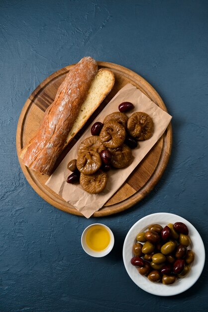 Bread long loaf, fig and dates on wooden board