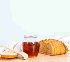 Foto gratuita impani la fetta e il barattolo di miele per la prima colazione sopra lo scrittorio di legno