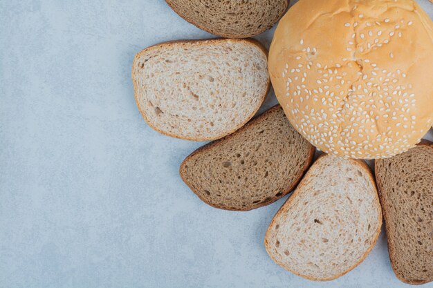 Bread slices and bun with sesame seeds on blue background. High quality photo