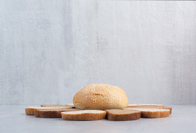 Ломтики хлеба и булочка с кунжутом на синем фоне. Фото высокого качества