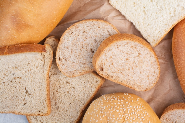Bread slices and bun with sesame seeds on paper sheet
