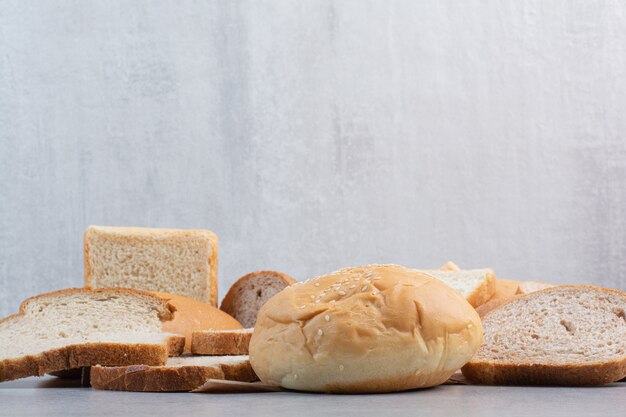 Bread slices and bun with sesame seeds on paper sheet