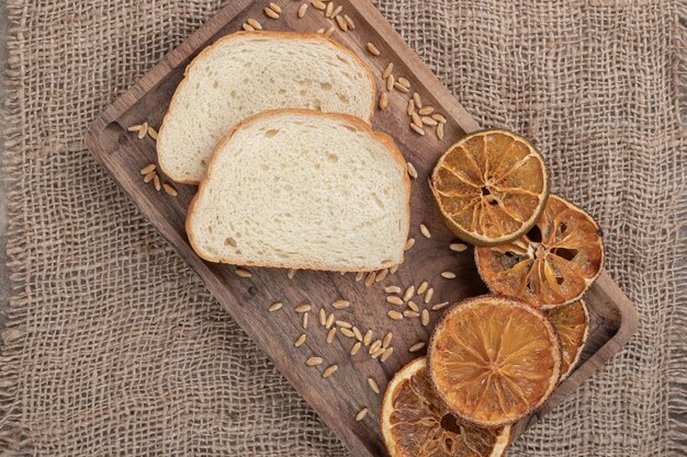 Free photo bread slices and dried orange on wooden plate. high quality photo