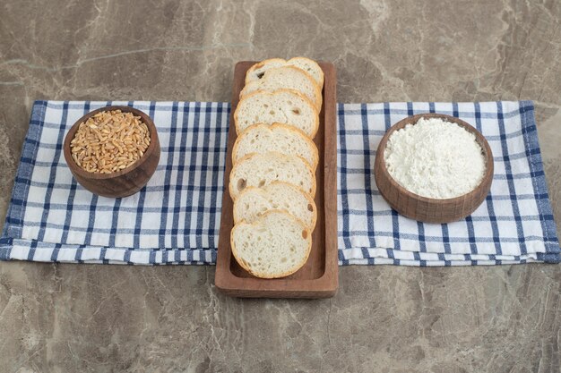 Fette di pane, farina e orzo sulla tovaglia. foto di alta qualità