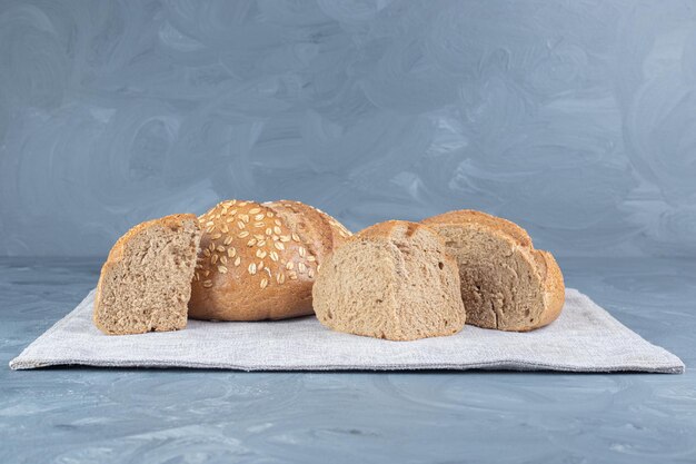 Ломтики хлеба на сложенной скатерти на мраморном столе.