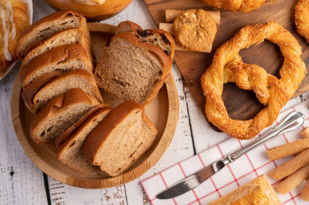 Bread slices placed in a wooden plate on a white wooden table.