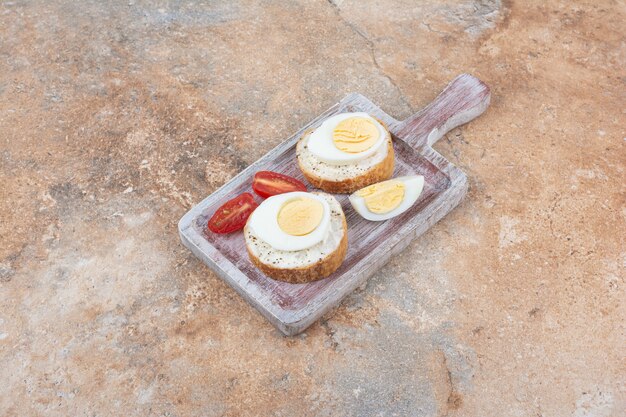 ゆで卵とトマトのスライスと木の板の上のパンのスライス