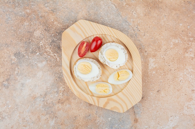 삶은 계란과 토마토 나무 접시에 빵 조각