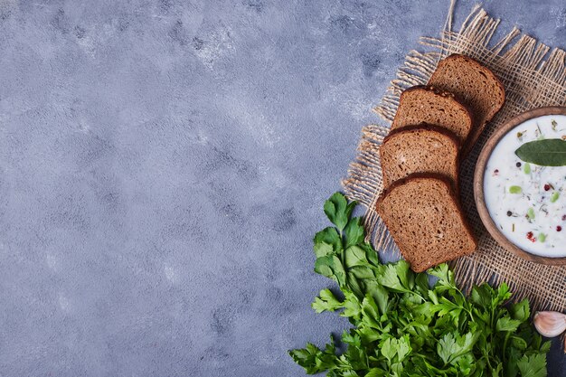 Bread slices with a cup of yogurt soup, parsley and garlics.