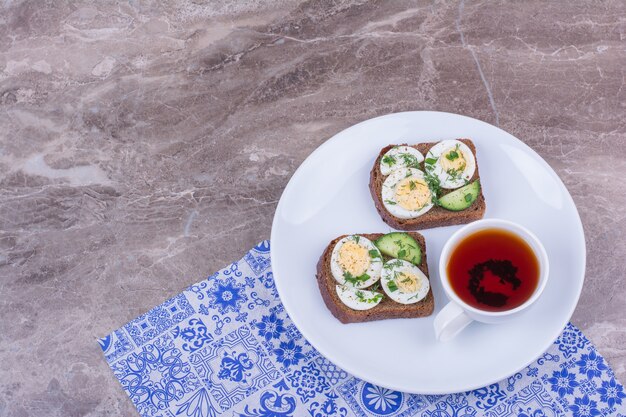 Bread slices with egg and herbs served with a cup of tea