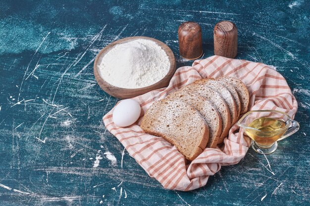 Bread slices with egg and oil on blue table.