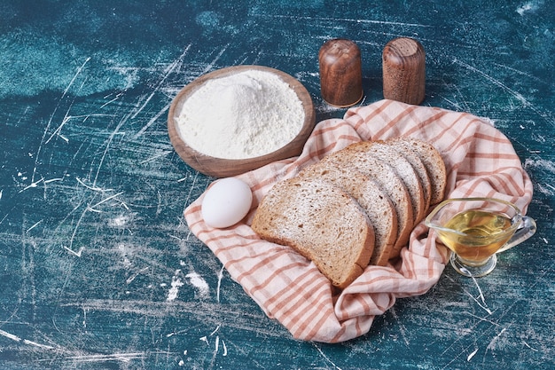 Bread slices with egg and oil on blue table.