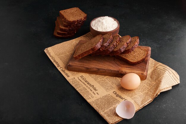 Bread slices with ingredients on the piece of newspaper. 