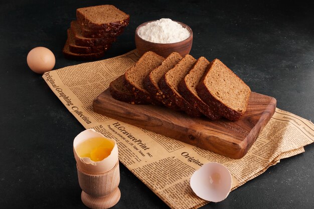 Ломтики хлеба с ингредиентами на деревянной доске