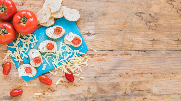 Bread slices with tomatoes and grated cheese on wooden table