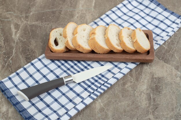 Bread slices on wooden plate with knife. High quality photo