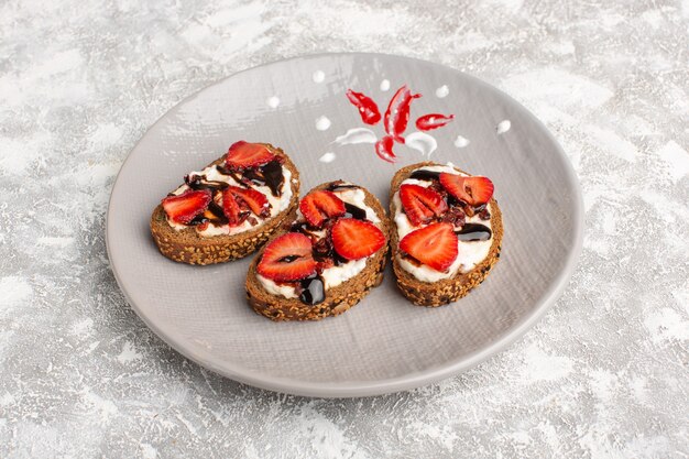 bread toasts with strawberries and sour cream inside plate on grey