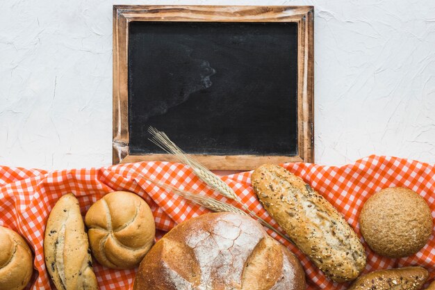 Bread and wheat on fabric near chalkboard