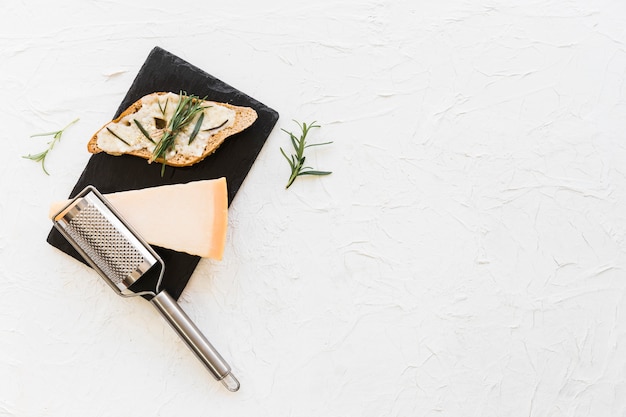 Bread with cheese and rosemary on stone plate on white backdrop