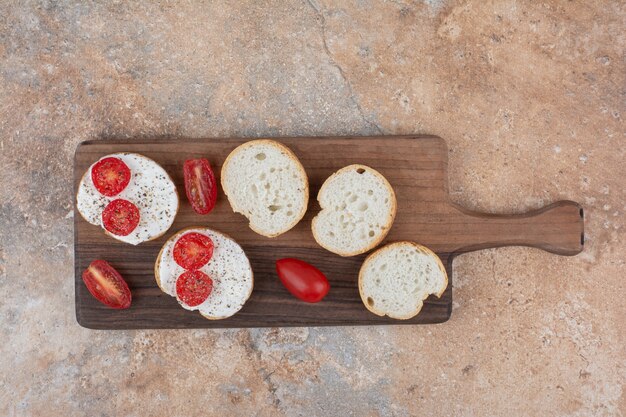 木の板にクリームとトマトのスライスとパン
