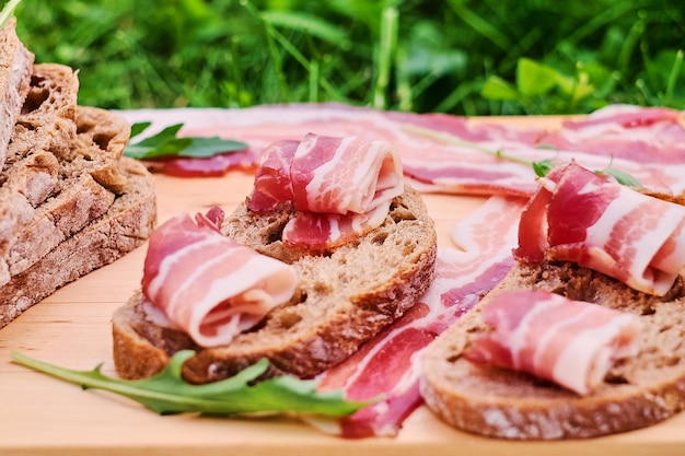Bread with gourmet meat on a wooden desk over green lawn background.