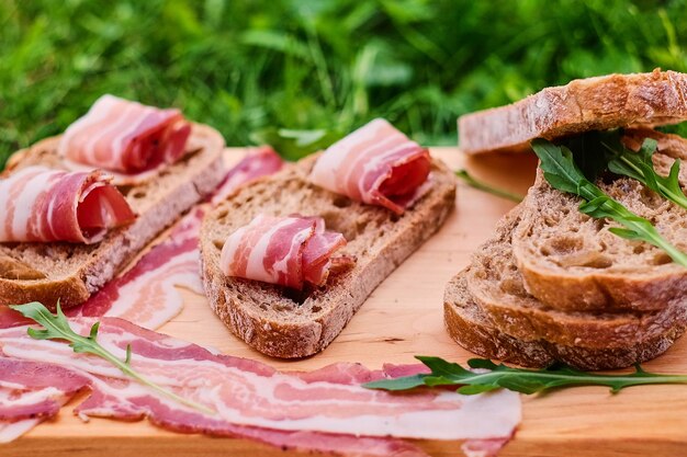 Хлеб с изысканным мясом на деревянном столе на фоне зеленой лужайки.