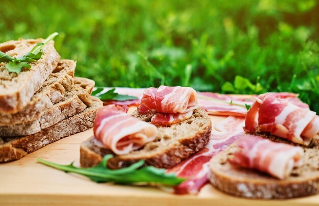 Bread with gourmet meat on a wooden desk over green lawn background.