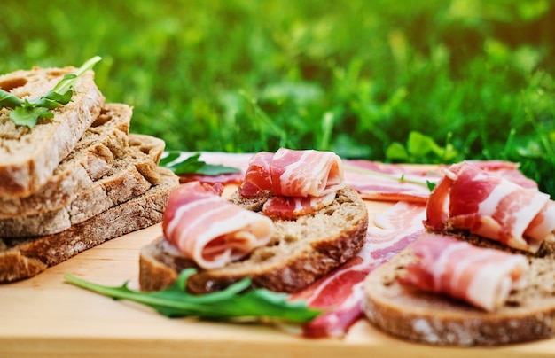 Bread with gourmet meat on a wooden desk over green lawn background.