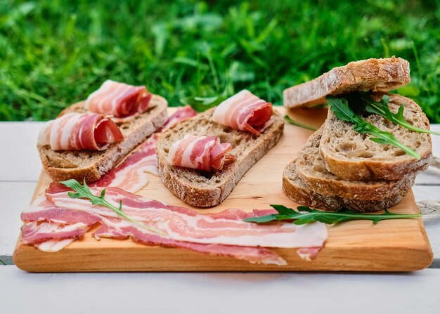 Bread with gourmet meat on a wooden desk over green lawn background.