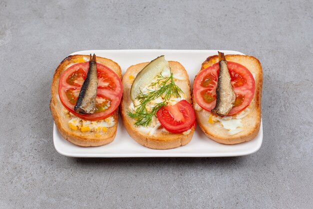 Bread with scrambled egg and fish on white plate