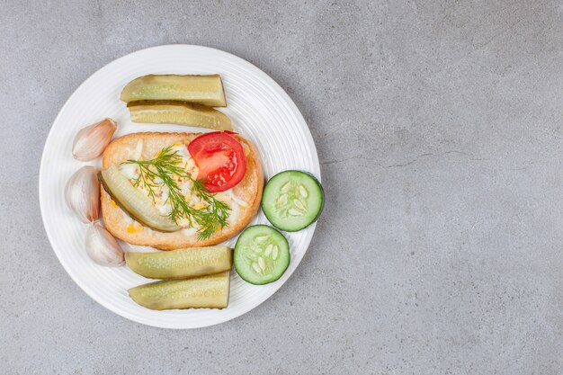 Bread with scrambled egg and pickles on white plate