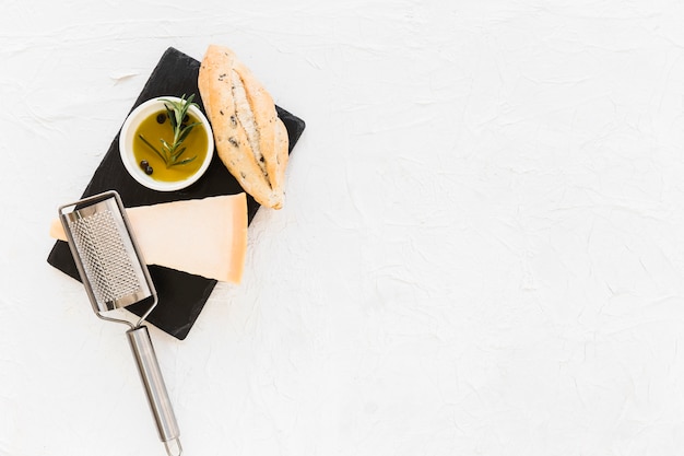 Pane con formaggio cheddar triangolare e olio d'oliva sul piatto di pietra