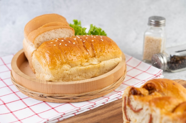 Bread in a wooden tray on a red and white cloth.