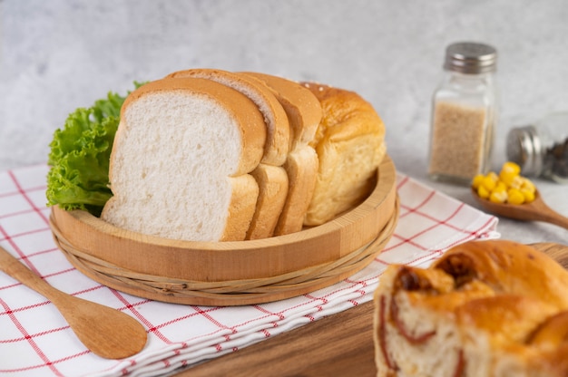 Bread in a wooden tray on a red and white cloth.