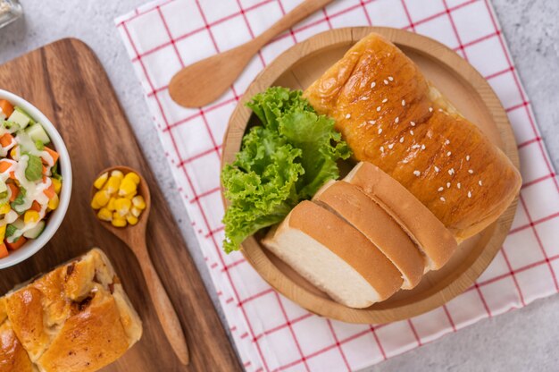 Bread in a wooden tray on a red and white cloth.