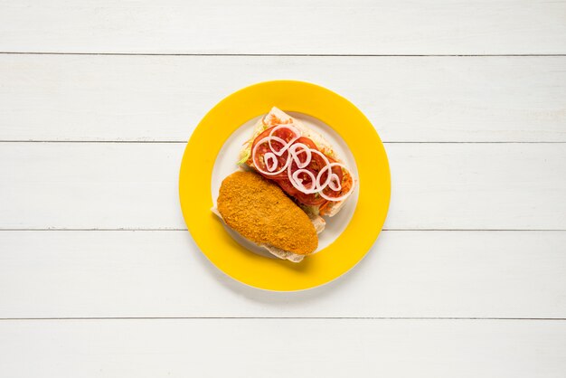 Панированная куриная грудка и сэндвич со свежими овощами на деревянном столе
