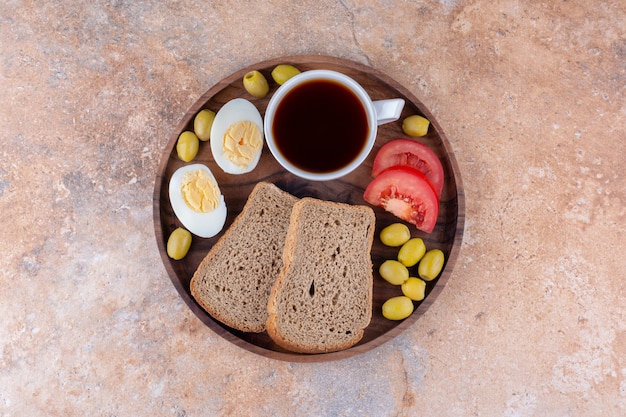 Breakfast board with bread slices, vegetable and a cup of tea