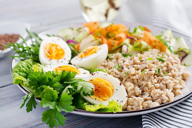 Breakfast bowl with oatmeal, zucchini, lettuce, carrot and boiled egg