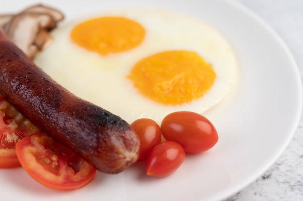 Colazione composta da pane, uova fritte, pomodori, salsiccia cinese e funghi.