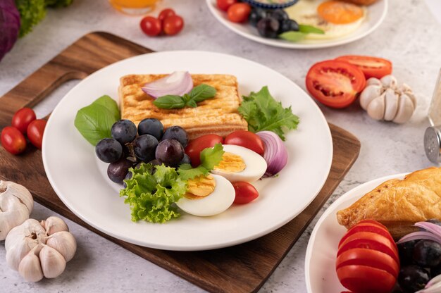 아침 식사는 빵, 삶은 계란, 검은 포도 샐러드 드레싱, 토마토 및 얇게 썬 양파로 구성됩니다.